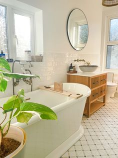 a white bath tub sitting next to a sink in a bathroom under a round mirror