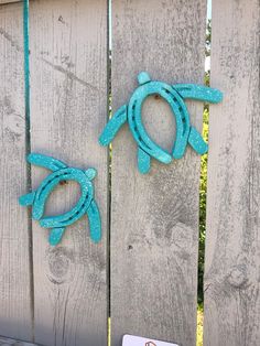 two blue sea turtle hooks on a wooden fence