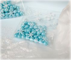 two bags filled with blue candy covered in snowflakes on top of a table