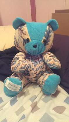 a blue teddy bear sitting on top of a bed