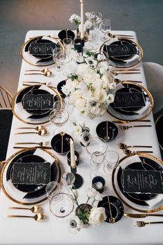 the table is set with black and white plates, silverware, and floral centerpieces