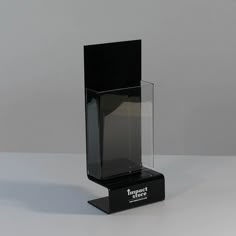 a black and clear display case on a white table with a gray wall in the background