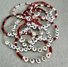 a bunch of beads that are sitting on the ground with words written in them and some charms attached to each bead