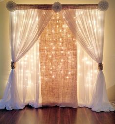 a curtain with lights hanging from it in front of a wooden floor and white curtains