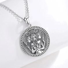 a silver necklace with an image of two people on the front and one in the back