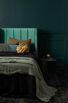 a bed with pillows and blankets on it in a room painted teal green,