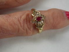 Ruby and Diamond Ring set with a natural marquise ruby that measures 5X2.5mm and is .20Carats.  The baguette and round diamonds surrounding the ruby measure approximately .50 Carats.  This is a dainty ring and very pretty on the hand.  It is solid 10K yellow gold and weight 3.2 grams.  Currently a size 6.75 (6 3/4)  The ring can be sized up or down as needed.  Ruby is July Birthstone.  Great engagement ring also.  Actual item is pictured but greatly enlarged for detail.  All measurements are tak Gold Ruby Ring With Baguette Diamonds For Anniversary, Vintage Ruby Rings, Filigree Diamond Ring, Diana Ring, Ruby Ring Vintage, Cats Eye Ring, Expensive Rings, Ruby And Diamond Ring, Diamond Ring Set