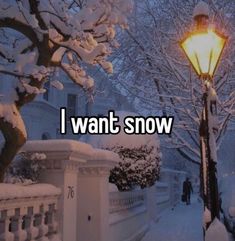 a street light covered in snow next to a white fence and tree with lots of snow on it