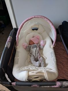 a baby laying in a stroller next to a wall