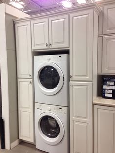 a white washer and dryer in a room with cabinets on the wall behind them