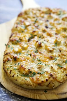 a cheesy pizza sitting on top of a cutting board next to a wooden spatula