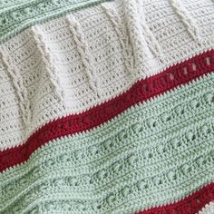 there is a blanket that has been crocheted on the bed with red, green and white stripes