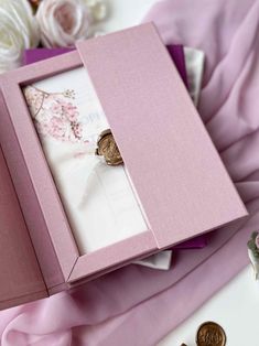 a pink box with some buttons in it and flowers on the table next to it