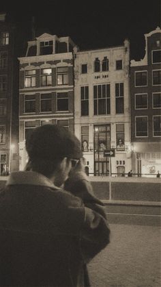 a man talking on a cell phone while standing in front of a building at night