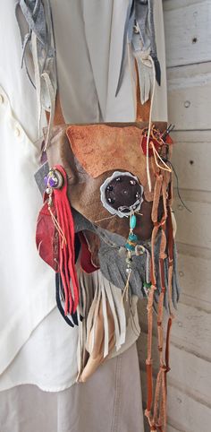 a woman wearing a leather mask with feathers and beads hanging from it's back