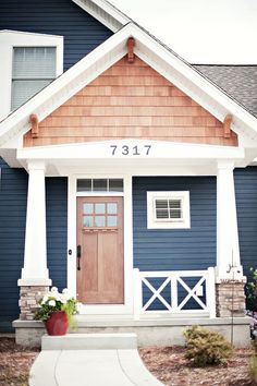 a blue house with white trim and wooden door is featured in this postcard photo