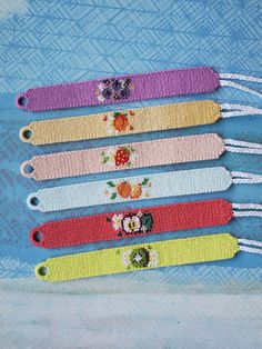 four colorful bracelets with flowers on them sitting next to each other in front of a blue background