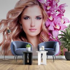 a woman with long blonde hair and blue chairs in front of a wall mural that has orchids on it