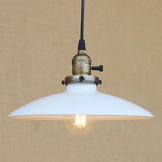 a white light hanging from a ceiling with a brown wall behind it and a tan curtain in the background