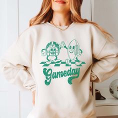 Hey there, football fan! Ready to infuse some retro charm into your game day attire? Our Gameday Football Green Sweatshirt, featuring playful green retro football characters, is perfect for showcasing your love for the game with a nostalgic twist. Whether you're at the stadium, hosting a tailgate party, or cheering from home, this sweatshirt blends comfort with vintage flair. Crafted from ultra-soft, high-quality fabric, our Gameday Football Green Sweatshirt ensures warmth and durability through Cheap Sweatshirt With Team Logo For Game Day, Green Top For Football Season Fan Merchandise, Green Tops For Football Season Fan Merchandise, Green Tops For Football Season, Green Tops For Football Season Sports Fans, Green Tops For Football Season Fan Gear, Green Fan Apparel Sweatshirt For Sports Events, Green Sweatshirt With Letter Print For Fans, Retro Tops For College Football Season