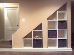 an empty room with some bookshelves and baskets on the floor in front of it