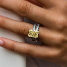 a woman's hand holding a yellow and white diamond ring