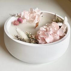 a white bowl with flowers and feathers in it