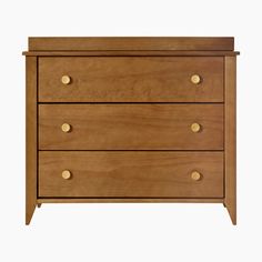 a wooden dresser with three drawers and gold knobs on the bottom drawer, against a white background