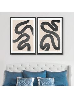 two black and white paintings hanging above a bed