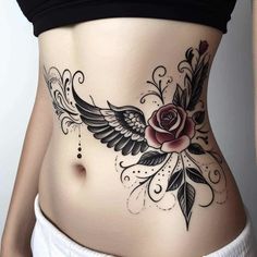 a woman's stomach with a rose and wings tattoo on the side of her belly