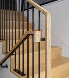 a close up view of a wooden stair case with black handrails and rails