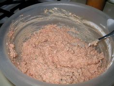 a mixing bowl filled with pink food on top of a stove next to a spatula