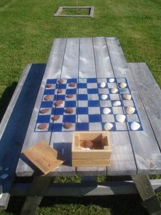 a checkerboard board game set up in the middle of a grassy area with benches