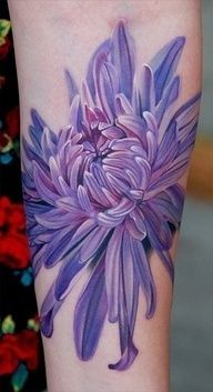 a woman's arm with a purple flower tattoo on the back of her leg