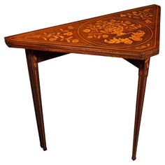 an ornately decorated table with wooden legs and a triangular shaped design on the top