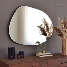 a mirror sitting on top of a wooden dresser next to a vase filled with flowers