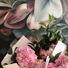 a bouquet of pink flowers sitting on top of a table next to a floral wallpaper