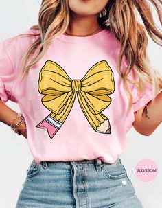 Capture the charm of school days with our "School Days Delight" T-shirt! This adorable tee features a cute bow shaped like a pencil and a retro school bus adorned with hearts on the back. Perfect for teachers, students, or anyone nostalgic for the joys of school, this shirt blends sweet and vintage vibes effortlessly. Made from soft, comfortable fabric, it's ideal for everyday wear or special occasions. Show off your love for learning and bring a touch of cuteness to your wardrobe with this delightful design! Fun Pink T-shirt For School Events, Playful Pink T-shirt For School, Preppy Pink Tops For School, Preppy Pink Top For School, Pink School Spirit T-shirt For Back To School, Pink T-shirt For Back To School, Trendy Back To School T-shirt For School, Kawaii Letter Print Tops For School, Pink School Spirit T-shirt For School