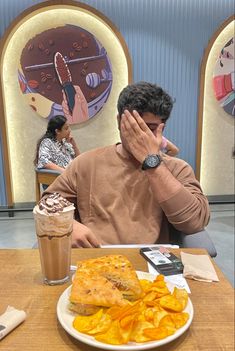 a man sitting at a table in front of a plate of food with chips on it