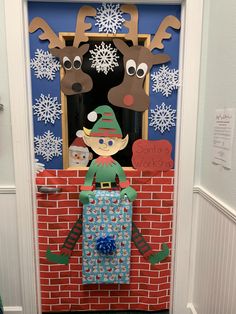 a door decorated to look like a christmas scene with reindeers and a boy holding a present