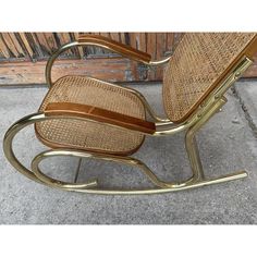 a rocking chair made out of wicker and leather with gold metal trimmings