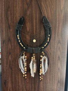 a dream catcher hanging on the wall with beads and feathers attached to it's sides