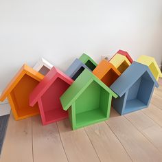 a group of multicolored houses sitting on top of a hard wood floor next to a white wall