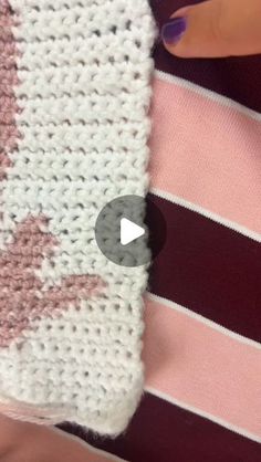 someone is crocheting a pink and white striped sweater with an arrow on it