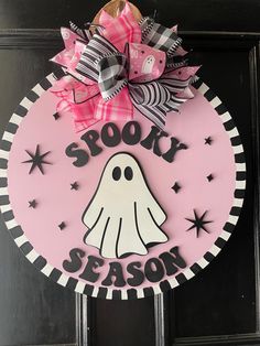 a pink door hanger with a black and white sign that says spooky season