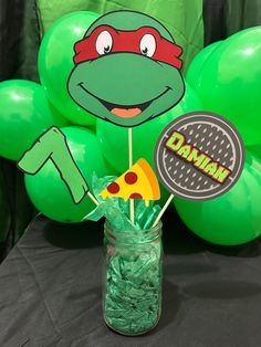 a jar filled with candy sitting on top of a table next to some green balloons