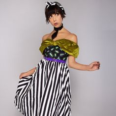 a woman in a striped dress posing with her hands on her hips and one hand on her hip