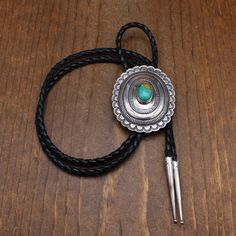 Vintage sterling silver and turquoise oval bolo tie. The center is domed and stamped. The silver is 2 3/4" tall x 2 1/4" wide. The turquoise is 17mm tall x 12mm wide. The cord and tips are 42" long. There is no maker's hallmark. The outside edge is scalloped. The bolo is in good condition. Thank you for shopping in our store. Please let us know if you have questions. BOLO-1293K k *The color you see on your screen may not reflect the actual stone color due to variations in monitors* Artisan Turquoise Bolo Ties With Concho, Vintage Turquoise Bolo Tie For Rodeo, Vintage Turquoise Bolo Ties For Rodeo, Western Style Oval Engraved Jewelry, Western Style Oval Concho Jewelry, Western Oval Engraved Jewelry, Bolo Ties, Bolo Tie, Tucson Az