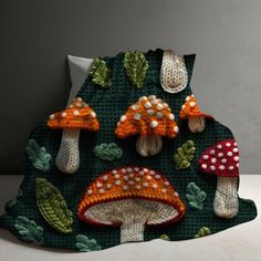 a crocheted blanket with mushrooms and leaves on it