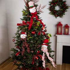 a decorated christmas tree with red and green ribbons, snowmen and wreaths on the top